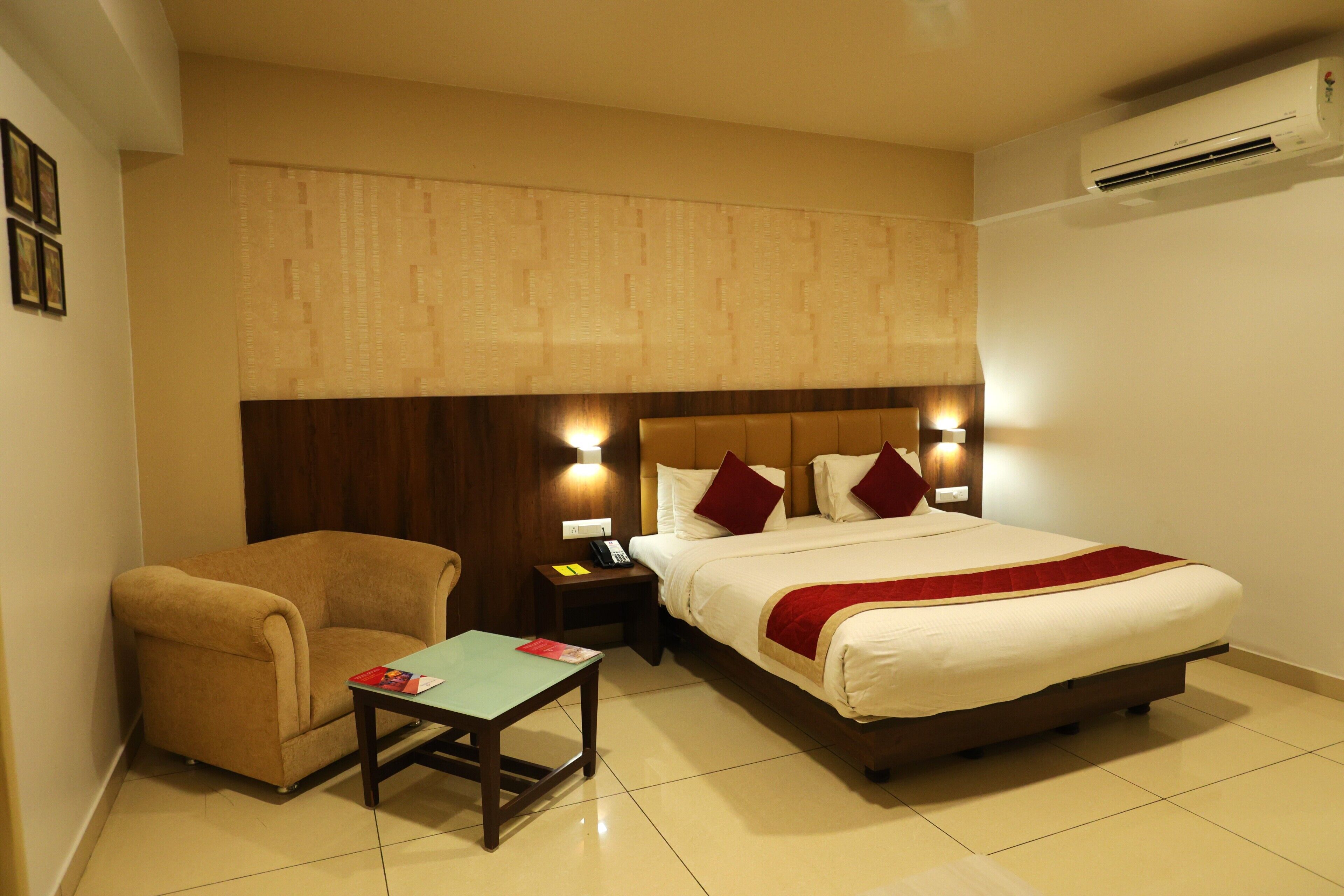 A hotel room with a bed, a chair, a nightstand, and a table.
