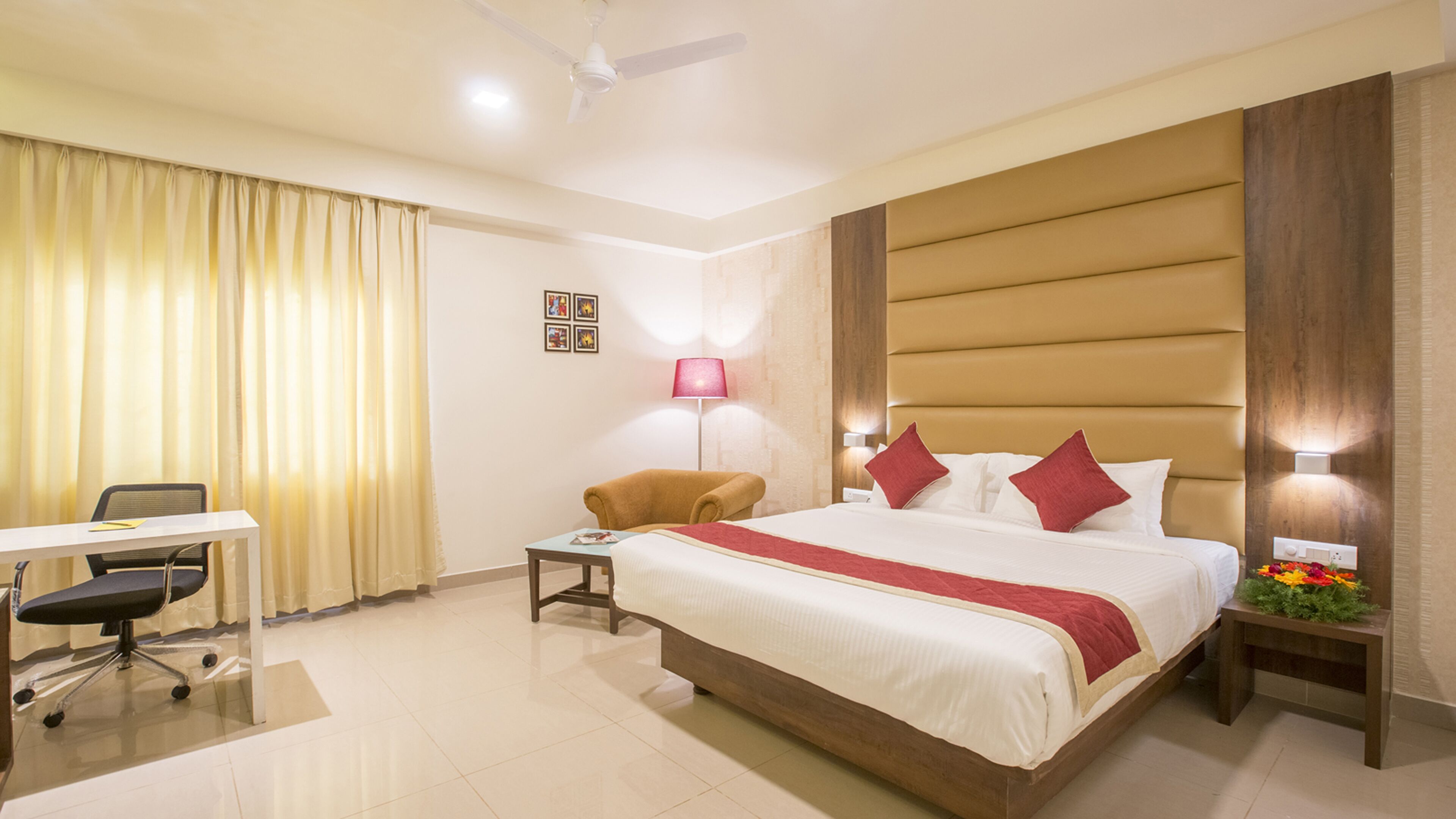 A hotel room with a bed, desk, chair, and a ceiling fan.