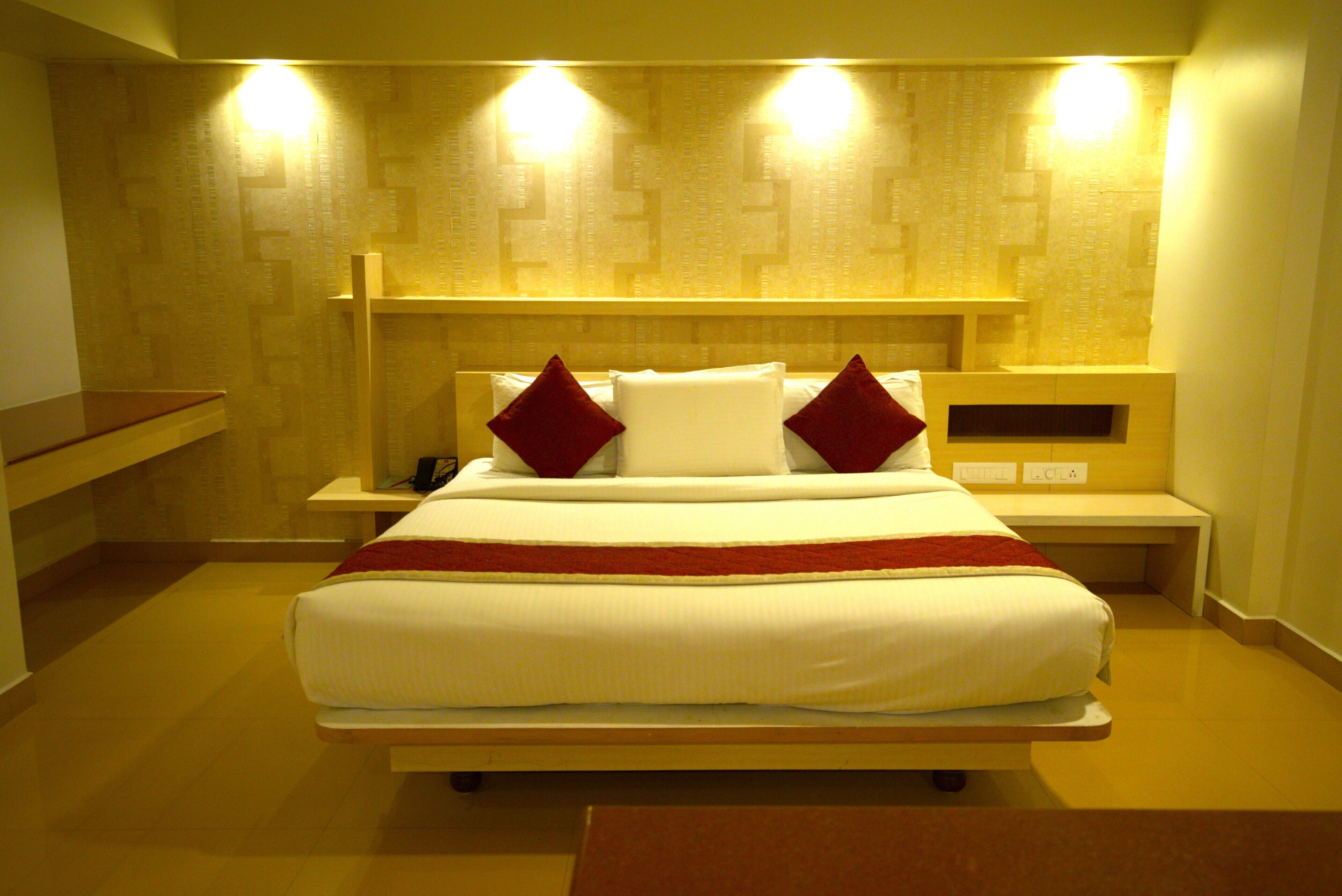 Una habitación de hotel moderna con una cama grande, dos mesitas de noche y un banco empotrado a lo largo de la pared.
