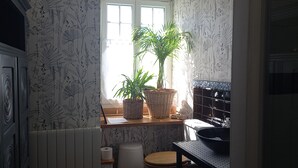 A bathroom with a window, a sink, a toilet, and two potted plants. - Family home in country with pool, lovely private gardens. Sleeps 6             (Jugon-Les-Lacs - Commune Nouvelle)