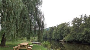A picnic table by a river with trees in the background. - Cozy chalet in a quiet, green area (Rendeux)