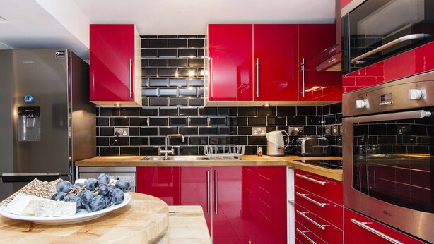A modern kitchen with red cabinets, stainless steel appliances, and a wooden countertop.