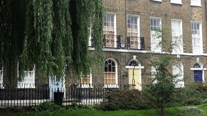 A two-story brick building with multiple windows and a balcony.