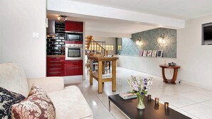 A modern living room with a sofa, a coffee table, and a dining area with a wooden table and chairs.