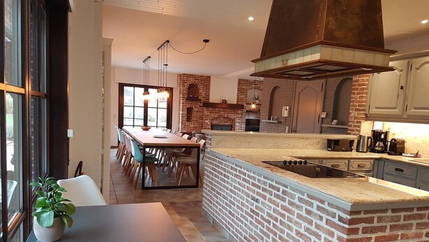 Una cocina moderna con un salpicadero de ladrillo, una isla grande y un comedor con mesa y sillas.