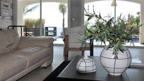 A modern living room with a sofa, a coffee table with a vase, and a chair.