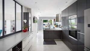 A modern kitchen with sleek cabinetry, a central island, and a large window providing natural light.