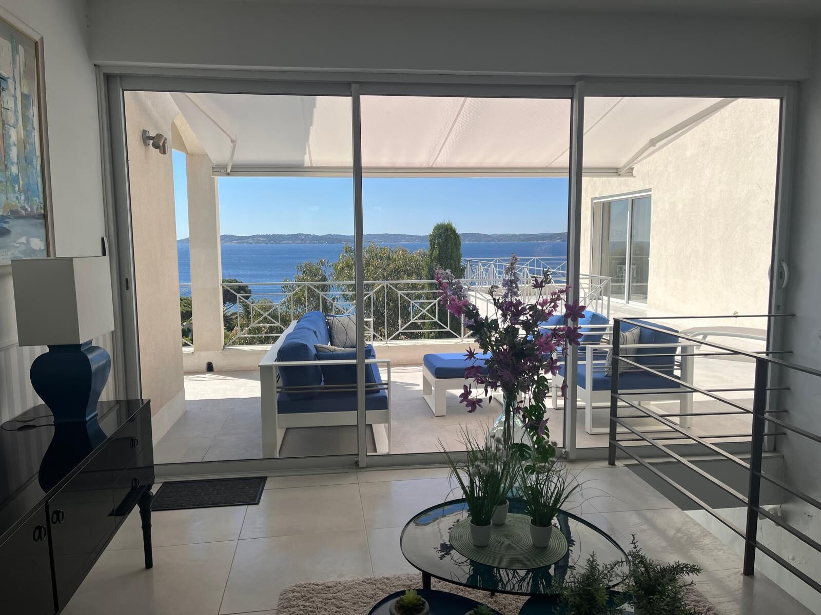 Un salon moderne avec une porte vitrée donnant sur un balcon d’où l’on peut admirer la mer.