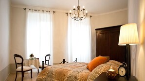 A bedroom with a bed, two chairs, a table, a lamp, and a clock. - La Finestra sul Teatro  (Cortona)