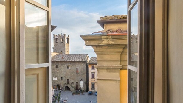 A view from a window overlooking a courtyard with stone buildings and a tower. - La Finestra sul Teatro  (Cortona)