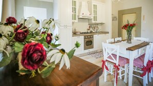 A kitchen with white cabinets, a stove, and a chandelier. - La Finestra sul Teatro  (Cortona)