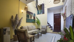 A living room with a sofa, coffee table, and chairs, a patterned rug, and a staircase leading to an upper level.