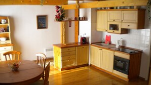 A kitchen with wooden cabinets, a dining table with chairs, and a small refrigerator.