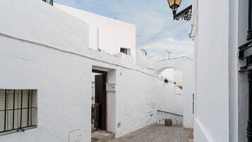 Un estrecho callejón con edificios blancos, una puerta de madera y un portón de metal.