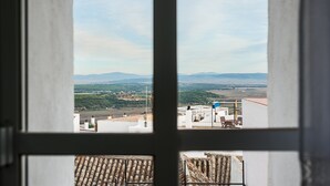 A view through a window of a building with a terrace, outdoor seating, and a distant landscape. - Centro Vejer Apartment with Terraces and Beautiful Views (Vejer de la Frontera)