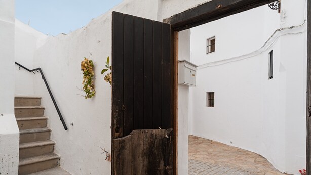A narrow alleyway with a wooden door, a staircase, and a white wall. - Centro Vejer Apartment with Terraces and Beautiful Views (Vejer de la Frontera)