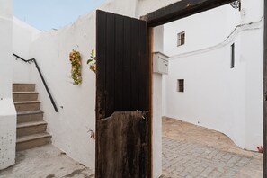 Une ruelle étroite avec une porte en bois, un escalier et un mur blanc.