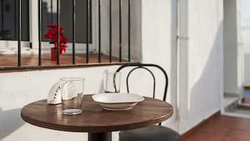 A round wooden table with a white plate, a clear glass, and a white napkin holder.