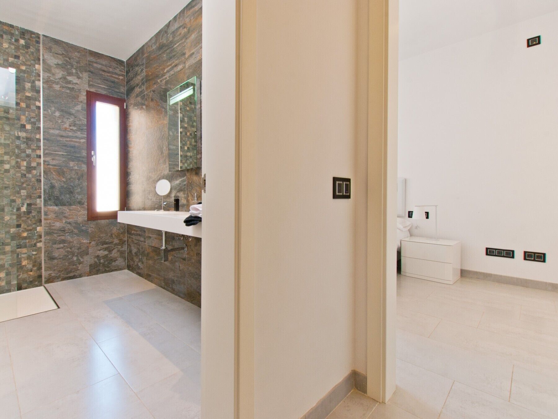 Une salle de bain moderne avec un mur en pierre, un lavabo et un miroir.