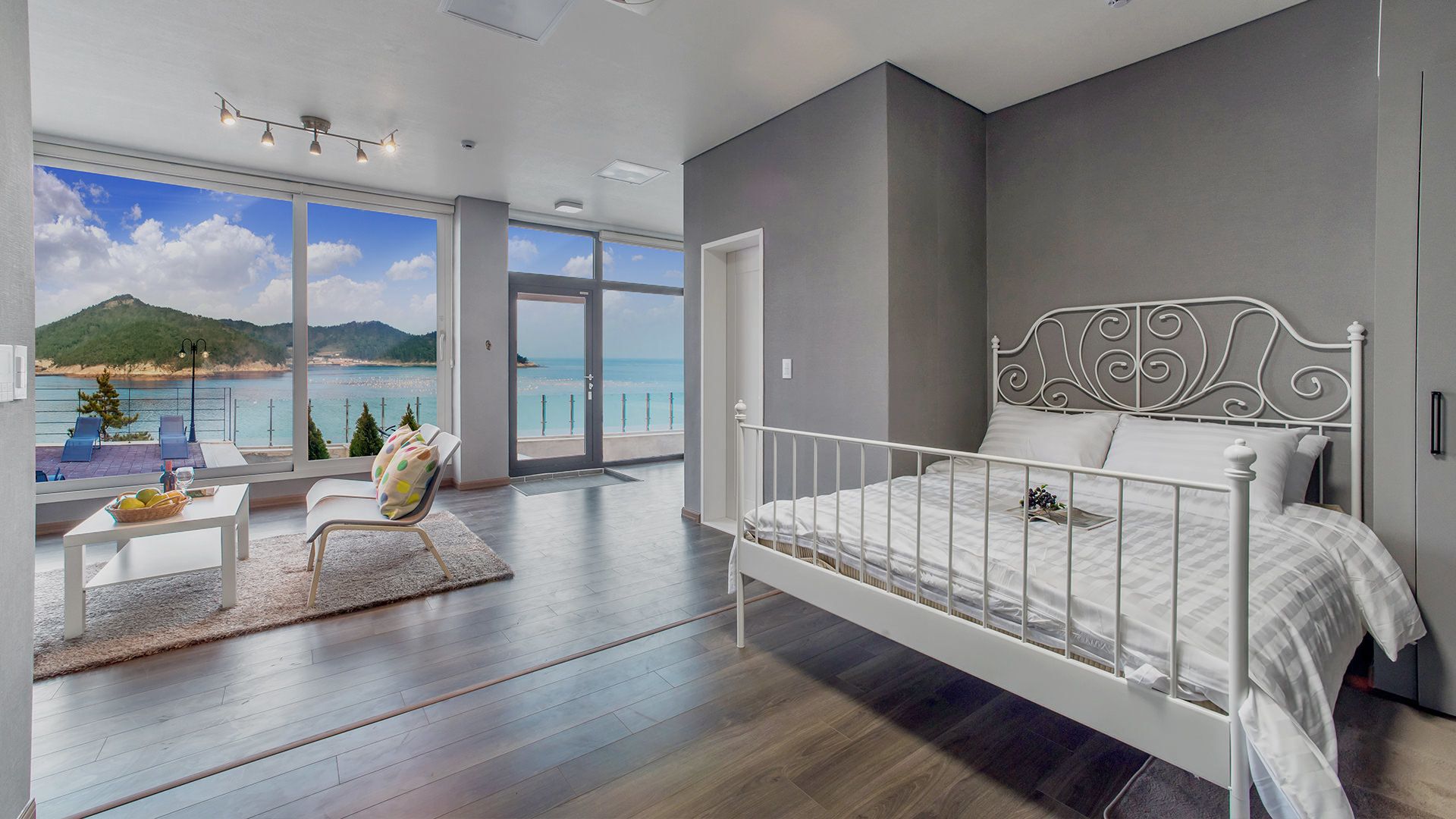 A bedroom with a bed, a view of the sea, and a balcony with seating.