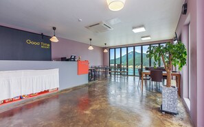 A reception area with a counter, chairs, tables, and a view of the sea. - Good Time Resort (Yeosu)