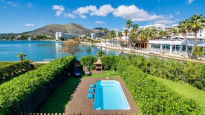 A pool area with a view of a body of water, a mountain, and a resort building.