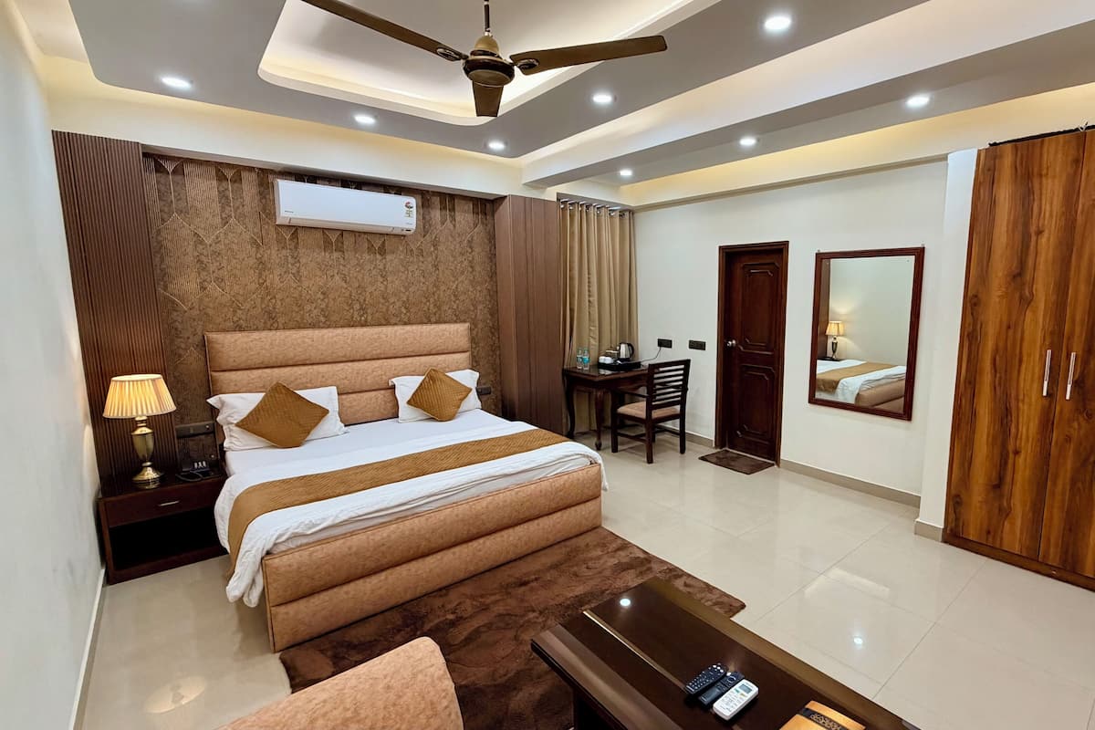 A modern hotel room with a large bed, a desk, a chair, a wardrobe, and a ceiling fan.