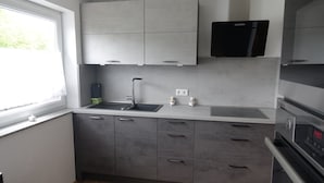 Une cuisine moderne avec des meubles gris, un micro-ondes noir et un four encastré.