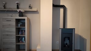 Une pièce avec un meuble en bois, un poêle noir et une étagère ornée d’objets décoratifs.