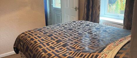 Een slaapkamer met een bed, een deur en een raam met gordijnen.
