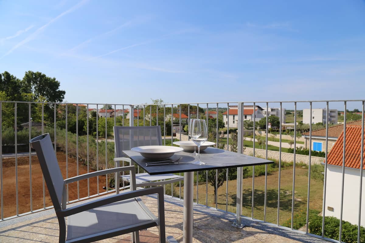 A balcony with a table set for two, overlooking a residential area.