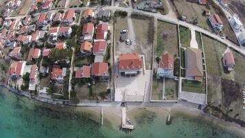 An aerial view of a coastal residential area with houses, a marina, and a road.