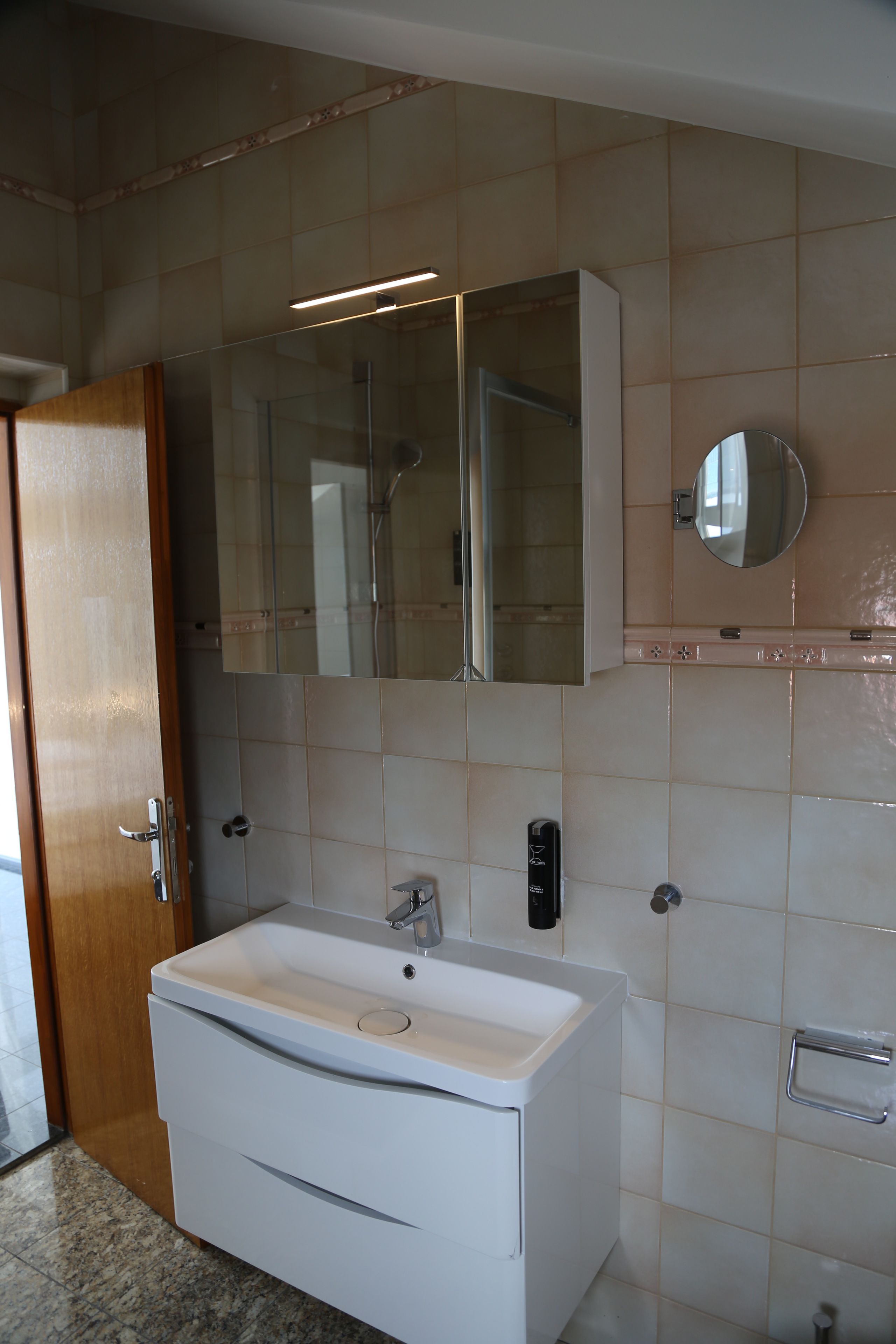 A bathroom with a white sink, a mirror, and a shower enclosure.