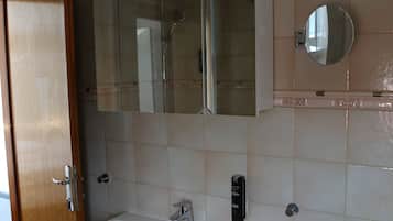 Un baño con un lavabo blanco, un espejo y una cabina de ducha.