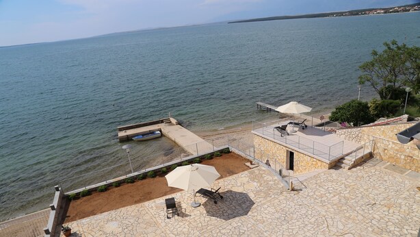A stone patio with outdoor seating and a view of the sea. - mk | apartments nin (Vrsi)
