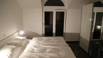 A bedroom with a bed, a wardrobe, and a door leading to another room.