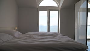 A bedroom with a large bed, a skylight, and a view of the sea. - mk | apartments nin (Vrsi)