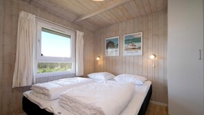 Ein Zimmer mit Holzwänden, einem Bett mit weißer Bettwäsche, zwei Wandleuchten und zwei gerahmten Bildern.