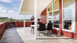 Ein überdachter Außenbereich mit Holzterrasse, Tisch und Stühlen.