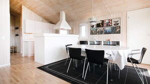 Eine moderne Küche mit weißen Schränken, einer zentralen Kochinsel und einem Essbereich mit rundem Tisch und Stühlen.