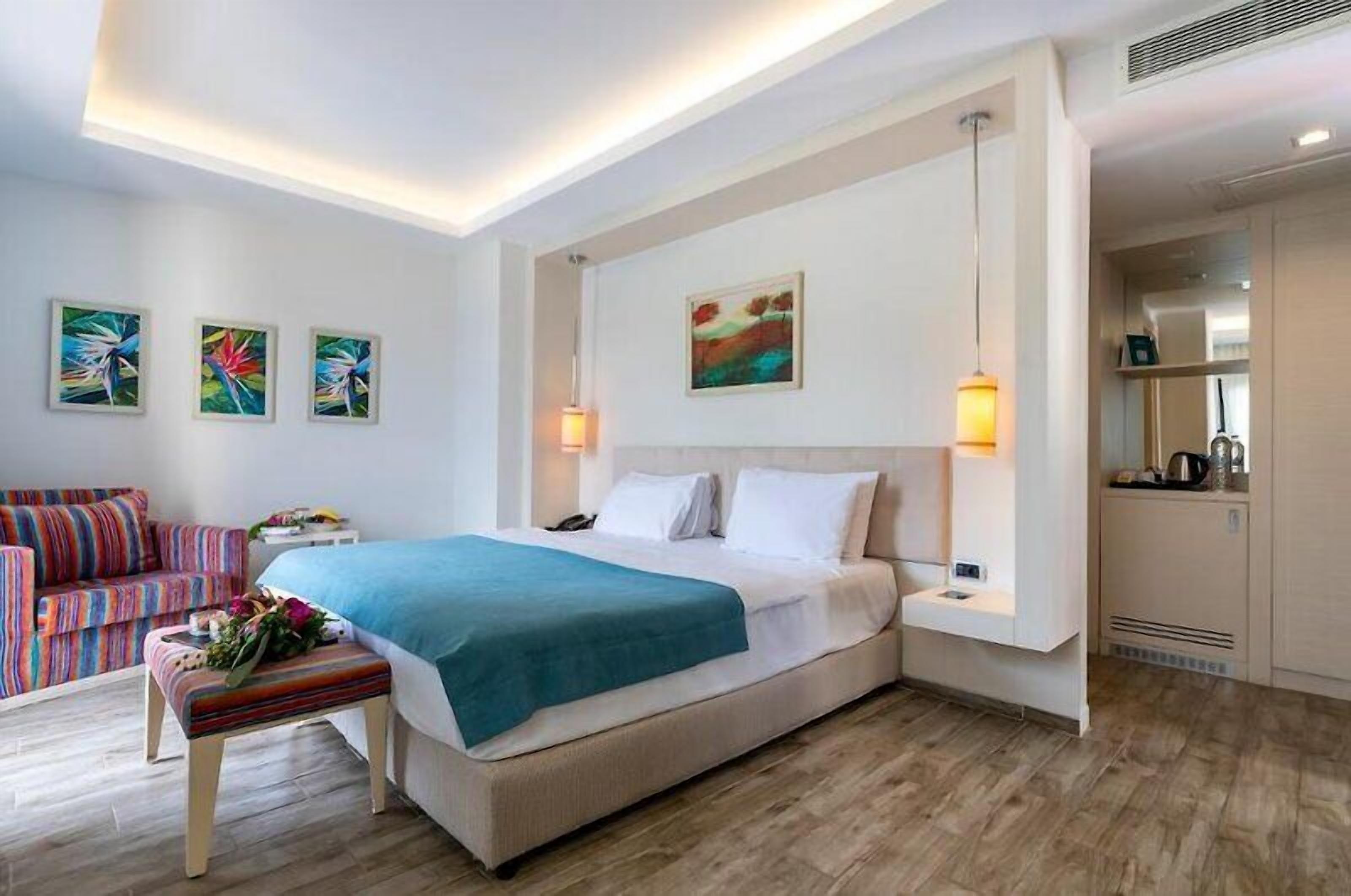 Ein modernes Hotelzimmer mit einem Bett, Nachttischen, einer Sitzecke und einer Küchenzeile.