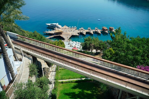 A bridge with a view of a marina and boats, surrounded by greenery and a clear sky. - Duja Bodrum - All Inclusive (Bodrum)