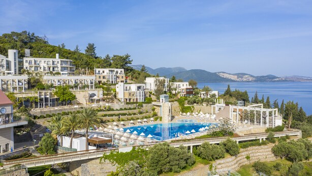 A coastal resort with a large swimming pool, multiple buildings, and a view of the sea. - Duja Bodrum - All Inclusive (Bodrum)