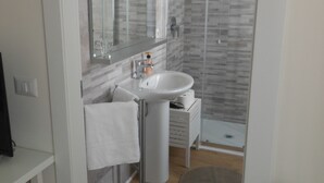 A modern bathroom with a white sink, mirror, and shower. - Affittacamere Risorgimento (Lecco)