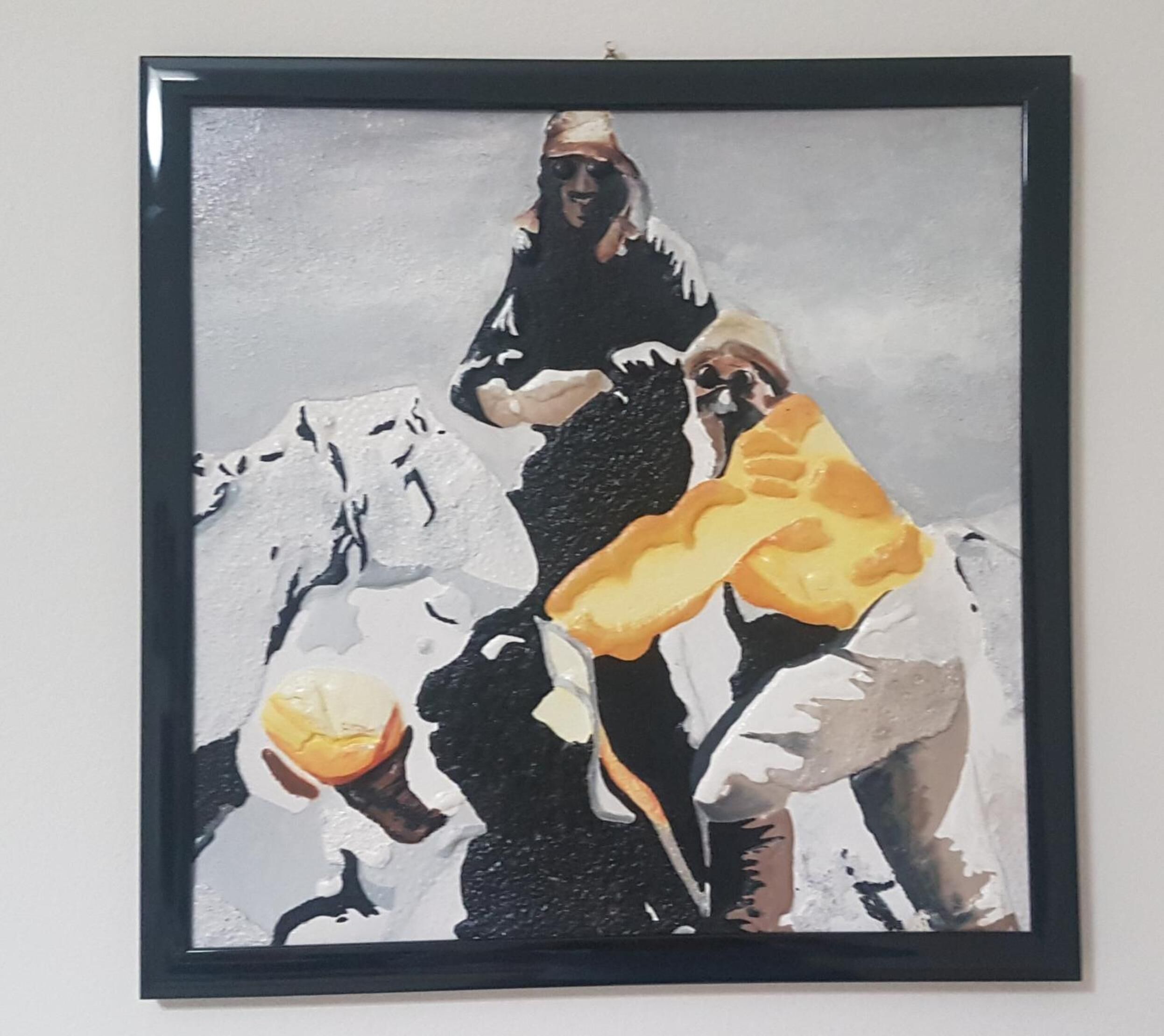 A framed artwork depicting a person climbing a mountain with a large yellow object.