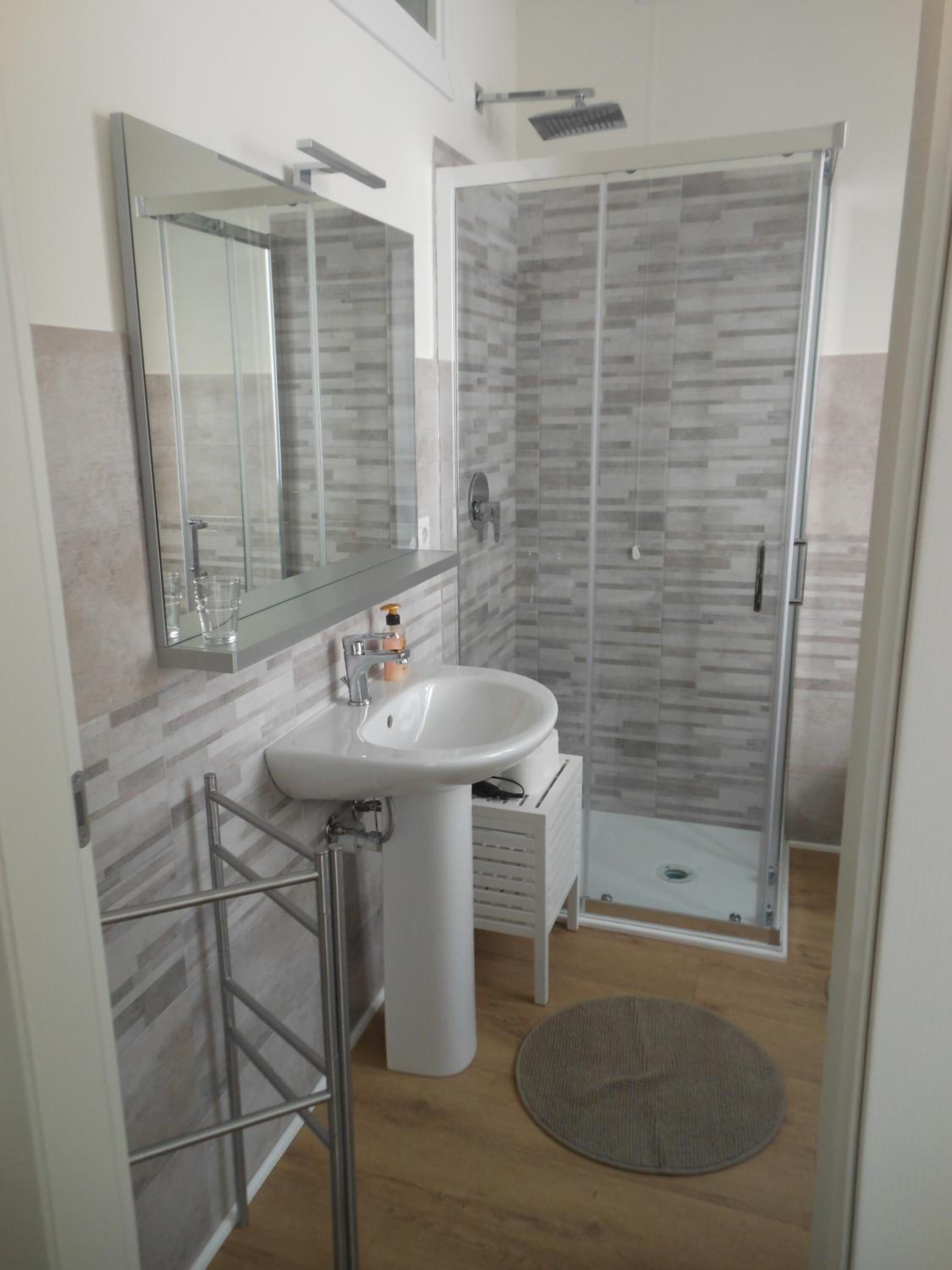 Een moderne badkamer met een douchecabine van glas, een wit wastafelmeubel en een grote spiegel.