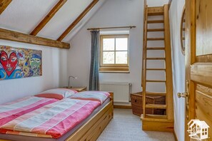 A cozy bedroom with a wooden bed, a window with curtains, a radiator, and a ladder. - Cozy, comfortable country house in a dream location (Templin)
