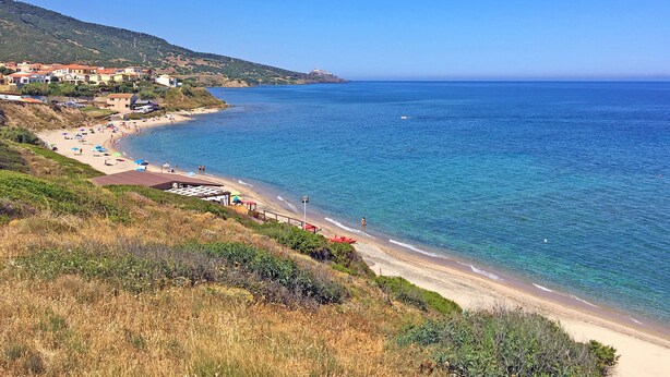 A coastal beach with clear blue waters, a sandy shore, and buildings in the background. - Holiday houses Sa Fiorida type Milli / 2 - Mediterranean style with 4 bedrooms (Valledoria)