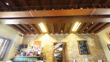 A rustic interior with exposed wooden beams, stone walls, and a bar area with various bottles and glasses.