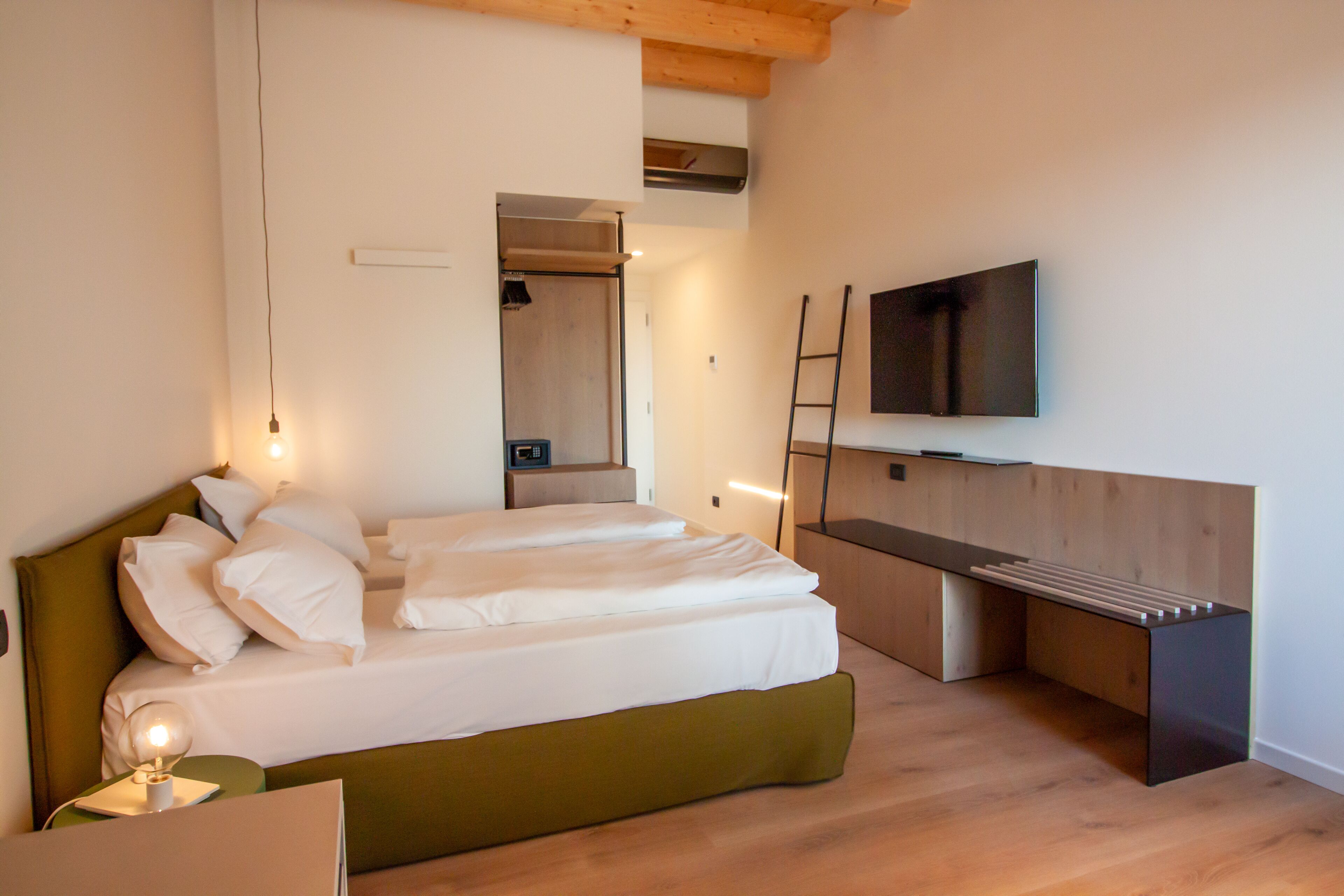 A modern bedroom with a bed, bedside table, and a TV mounted on the wall.